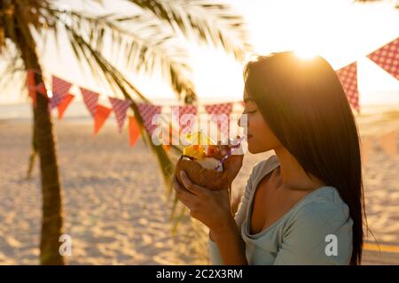 Giovane donna mista che beve cocktail sulla spiaggia Foto Stock