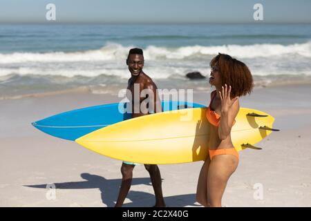 Felice coppia che tiene tavole da surf sulla spiaggia Foto Stock