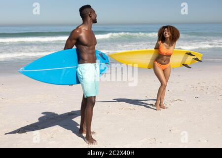 Felice coppia che tiene tavole da surf sulla spiaggia Foto Stock