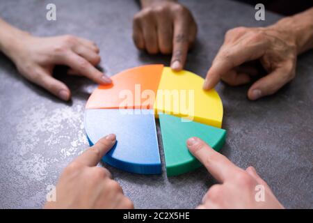 Uomini D'Affari Che Collegano Pezzi Di Torta Multicolore Grafico Sulla Scrivania Foto Stock