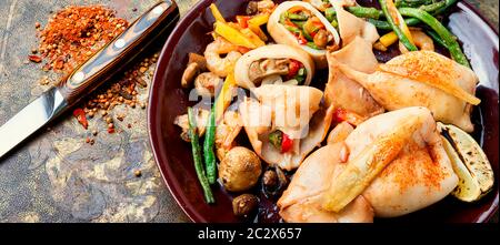 Frutti di mare al forno con verdure. Calamari ripieni di funghi e carote Foto Stock