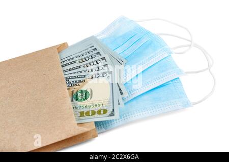 Maschere mediche blu e pila di banconote da 100 USD in pacchetto di carta marrone isolato su sfondo bianco Foto Stock