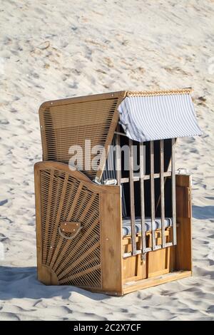 Una sedia da spiaggia chiusa si trova solo sulla spiaggia del Mar Baltico Foto Stock