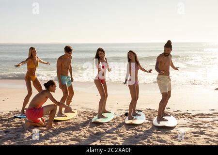 Gruppo multietnico di uomini e donne, surf sulla spiaggia Foto Stock