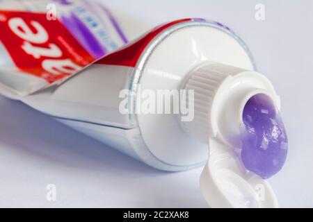 Blob di Colgate MaxWhite brillare cristalli dentifricio fluoruro che sgocciola dal tubo Set su sfondo bianco - dentifricio viola Foto Stock