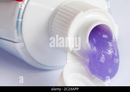 Blob di Colgate MaxWhite brillare cristalli dentifricio fluoruro che sgocciola dal tubo Set su sfondo bianco - dentifricio viola Foto Stock