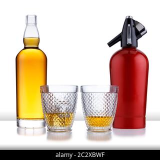 Una bottiglia piena di whisky dorato, senza etichetta o marchio, due bicchieri di whisky e un sifone retrò, isolato su bianco con un leggero riflesso Foto Stock