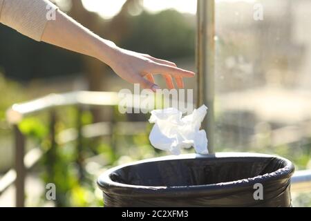 Primo piano di una mano donna che getta cucciolata in un cestino in un parco Foto Stock