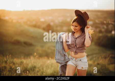 La ragazza è felice e gode della vita e ama la natura, passeggiate nei campi al tramonto Foto Stock