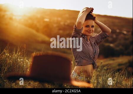 La ragazza cammina in un campo e gode la vita in strada al tramonto Foto Stock