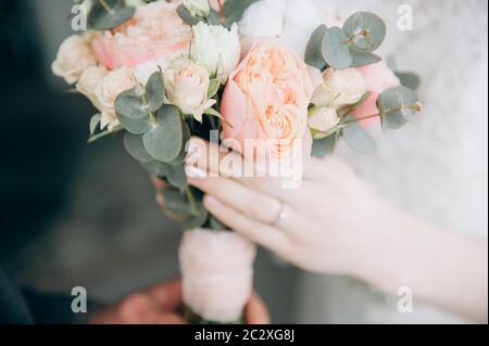 Il primo incontro dello sposo e dello sposo, lo sposo passa il bouquet di nozze alla sposa primo piano dei volti non visibili Foto Stock
