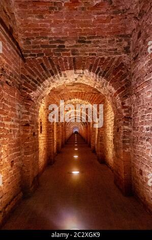 Arco in mattoni rossi come passaggio tra le due ali di un castello medievale. Granito pietra un mattone costruito interno Foto Stock