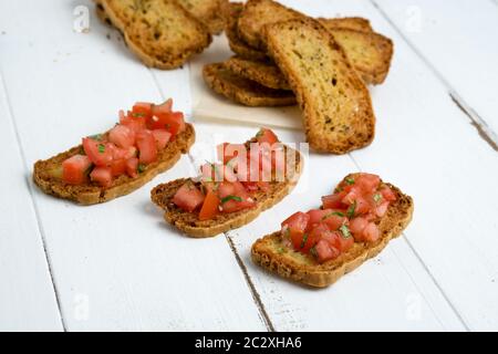 Bruschetta su sfondo bianco. La bruschetta è un antipasto molto popolare italiano, fatto di crostini (pane alla griglia) con pomodori a dadini. Foto Stock
