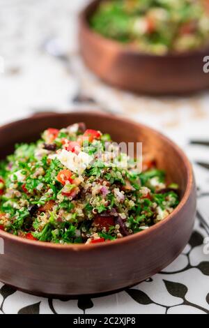 Piatto di quinoa per insalata. Questo piatto sano mescola tabbouleh e insalate in stile greco, utilizzando erbe fresche di prezzemolo, olive, cipolle, feta ecc. Foto Stock