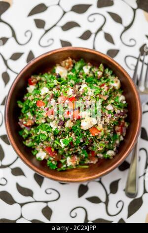 Ciotola sana dell'insalata dall'alto. Questo piatto sano mescola tabbouleh e insalate in stile greco, utilizzando erbe di prezzemolo fresco, olive, cipolle, feta . Foto Stock