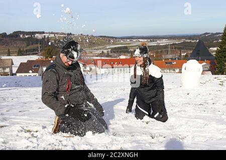 Una giovane coppia ha una lotta con la palla di neve in inverno. Una donna e un uomo si divertono nella neve Foto Stock