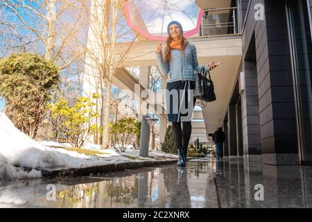 Donna che cammina attraverso le pozze della città in primavera Foto Stock