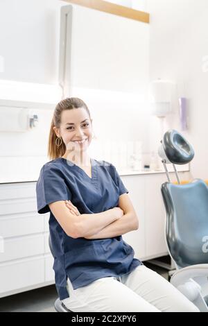 Giovane infermiera in giacca blu sorride nell'ufficio dentale prima di ricevere il paziente Foto Stock
