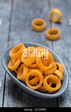 Anelli di patate su grigio legno rustico. Foto Stock