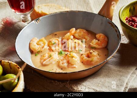 Scampi aragoste di formaggi con salsa di panna o kase sahne salsa servita in una piccola vecchia padella sulla biancheria in un ristorante in stile rustico o country house Foto Stock