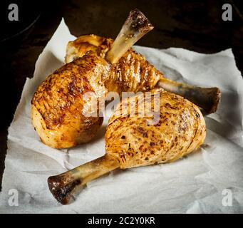 Tre piccante o alla brace speziato alla griglia cosce di pollo o bacchette accartocciata sul libro bianco in stretta fino Foto Stock