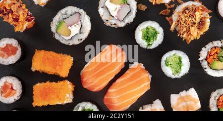 Grande set di sushi, un close-up panorama, ripresa dall'alto su uno sfondo nero. Un assortimento di vari maki, nigiri e rotoli Foto Stock