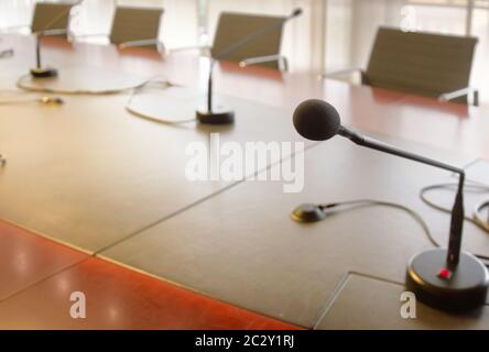 microfono su un tavolo di legno e sedie vuote in una sala riunioni Foto Stock