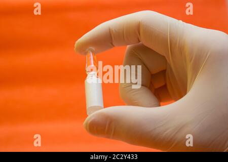 Ampolle con un farmaco per un vaccino contro le malattie, l'influenza nelle mani di un medico con guanti - cercare un vaccino, il trattamento dell'influenza, coron Foto Stock