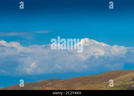 Ararat alto nevoso dietro le nuvole contro il cielo blu Foto Stock