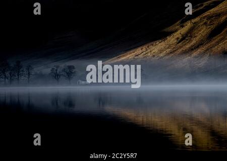 Dawn Mist sorge intorno a Buttermere, il lago nel Lake District inglese nel nord-ovest dell'Inghilterra. L'adiacente villaggio di Buttermere prende il suo nome Foto Stock