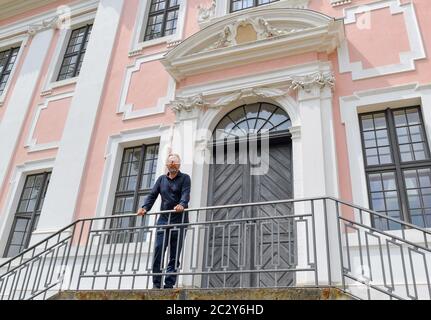 12 giugno 2020, Brandeburgo, Groß Rietz: Percy Bongers, proprietario del castello di Groß Rietz, si trova di fronte all'edificio barocco. "Non sono il signore del castello, ma l'arte", dice Percy Bongers. Il suo amore per il castello barocco Groß Rietz (Oder-Sprea) iniziò dieci anni fa, quando la casa padronale, che fu costruita intorno al 1700 ed è un edificio storico, era ancora un grande cantiere. La Brandenburgische Schlösser GmbH aveva preso il controllo della proprietà con la sua façade rosa e bianca dal comune a metà degli anni '90 per salvarla da ulteriore decadimento. Più di cinque milioni di euro sono confluiti nei restaurati Foto Stock