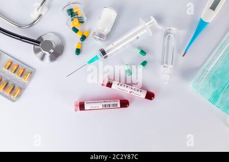 Provetta per analisi del sangue con la malattia di Coronavirus per analisi e ricerca dei virus. Provetta per analisi del sangue con maschere protettive, medicinali, termometro, stetoscopio a Foto Stock