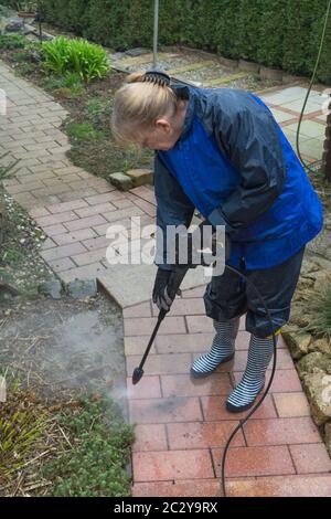 La donna pulisce in lastre di pietra con un lavaggio a pressione Foto Stock