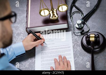 Giudicare la scrittura del documento con un martello e uno stetoscopio al banco Foto Stock