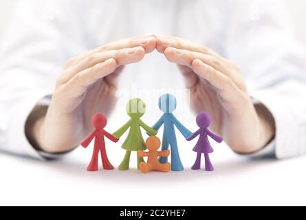 Concetto di assicurazione di famiglia con figurine colorate della famiglia coperte dalle mani Foto Stock