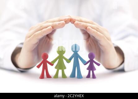 Concetto di assicurazione di famiglia con figurine colorate della famiglia coperte dalle mani Foto Stock