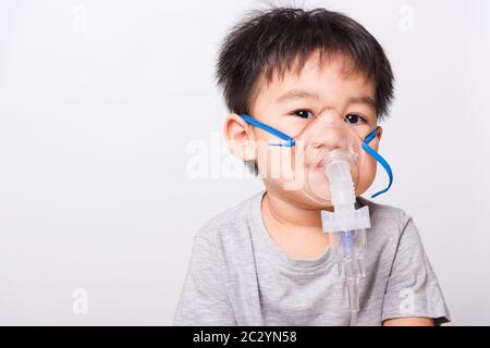 Closeup volto asiatico, Bambino Piccolo ragazzo malato che usa il vapore inalatore maschera nebulizzatore inalazione se stesso su sfondo bianco, sanità medica Foto Stock