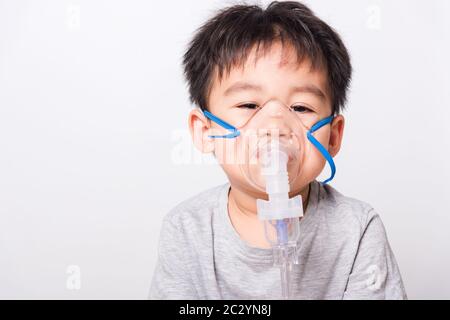 Closeup volto asiatico, Bambino Piccolo ragazzo malato che usa il vapore inalatore maschera nebulizzatore inalazione se stesso su sfondo bianco, sanità medica Foto Stock