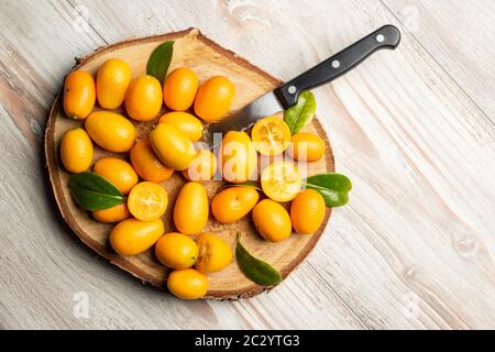 Mucchio di frutta di kumquat, tangerini cinesi, su tagliere di legno. Foto Stock