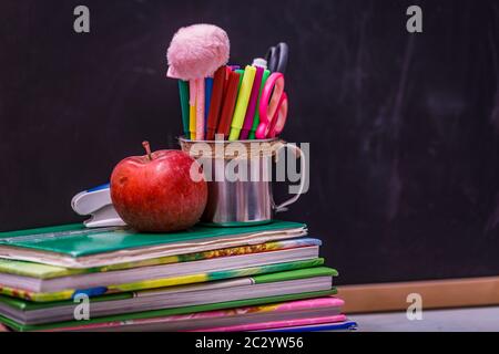 Ritorno a scuola con libri e mela su lavagna. Foto Stock