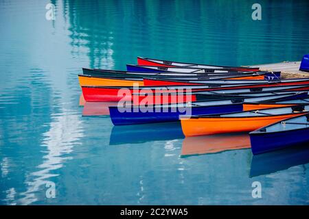 Colorate barche a remi ormeggiate in un lago calmo, Banff, Alberta, Canada Foto Stock