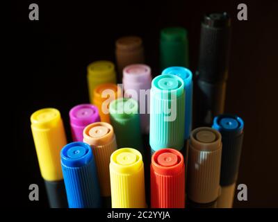 Ampio gruppo di penne colorate con punta in feltro e cappucci su sfondo scuro Foto Stock