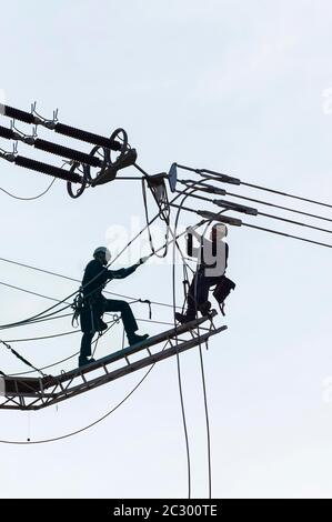Ingegneri ad alta tensione che lavorano su piloni ad alta tensione, Baden-Wuerttemberg, Germania Foto Stock
