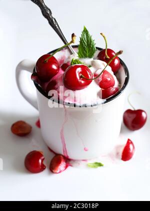 Concetto di cibo dolce. Gelato delizioso con ciliegia in una tazza bianca. Messa a fuoco selettiva. Foto Stock