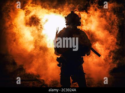 Silhouette di moderno soldato fanteria, combattente dell'esercito d'elite in munizioni tattiche e casco, in piedi con fucile di servizio d'assalto in mani su backgroun Foto Stock