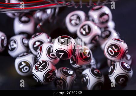 Palline di lotteria bianche e nere in una macchina 7 Foto Stock