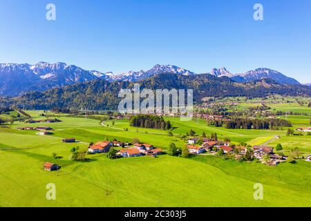 Villaggio di Hafenegg vicino Hopferau, paesaggio culturale di fronte al Tannheimer Berge con Hohe Schlicke, Brentjojch e Aggenstein, registrazione droni Foto Stock