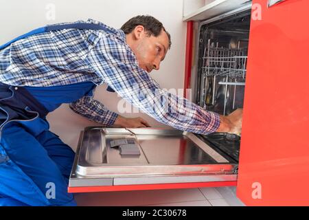 Foto Di Riparatori Che Esaminano La Lavastoviglie In Cucina Foto Stock