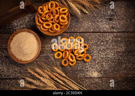 Piatto di tradizionali mini anelli di pretzel salati su sfondo di legno Foto Stock