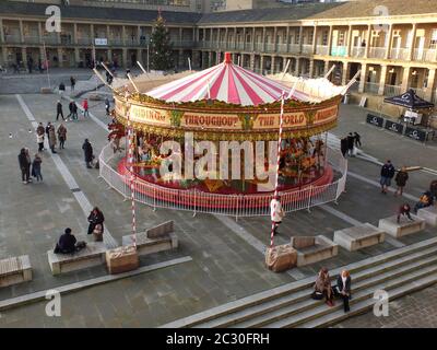 La gente si fermò a guardare una giostra d'epoca nelle vacanze di natale nella piazza pubblica di Halifax Piece Hall West yorkshire Foto Stock